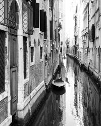 Boats moored in canal amidst buildings in city