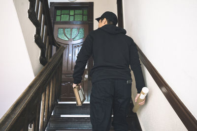 Rear view of delivery man with package climbing staircase