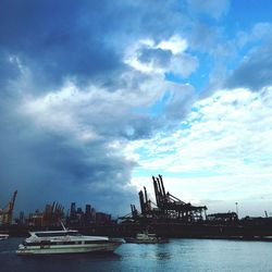 Boats at harbor against cloudy sky