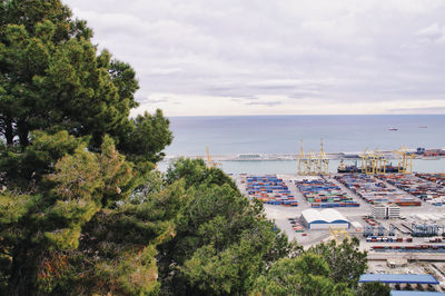 High angle view of trees and commercial dock against sky, barcelona 