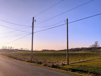 Road amidst field against sky during sunset