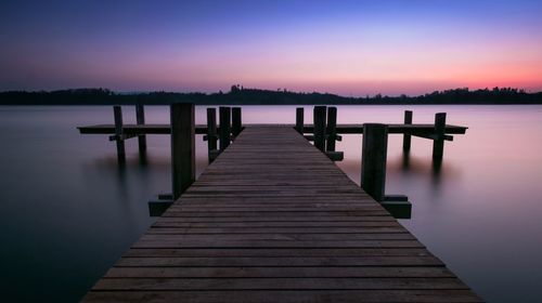 Pier over lake against sky during sunset