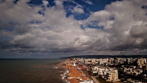 Aerial view of townscape by sea against sky