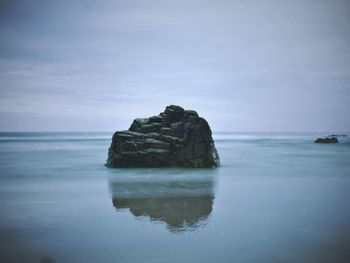 Rock formation in sea against sky