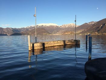 Wooden posts in lake against sky