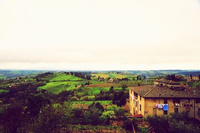 Houses on landscape against cloudy sky