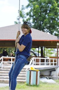 Playful woman hanging on rope against gazebo at public park