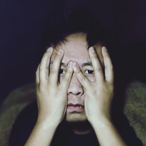 Close-up portrait of man covering face at night