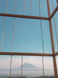 Low angle view of sea against clear blue sky seen through window