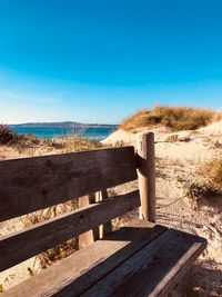 Wooden structure on footpath against clear blue sky