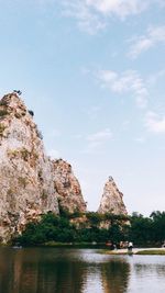 Rock formation by lake against sky