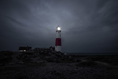 Lighthouse at night pulsing a beam of light across the sky.