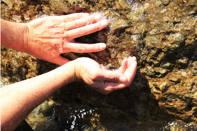 Midsection of person hand on rock