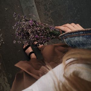 Low section of woman relaxing on purple flowering plant