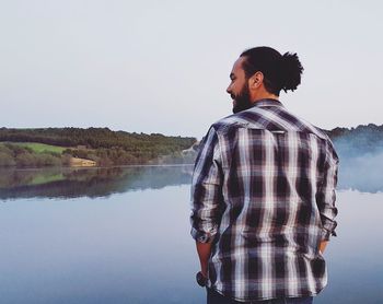 Young man looking at lake against sky