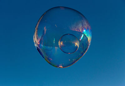 Close-up of soap bubble against clear blue sky