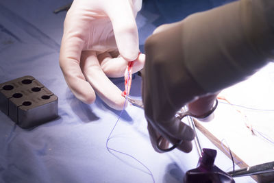 Cropped hands of doctor cutting stitches over table