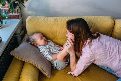 Side view of mother and daughter sitting on sofa at home