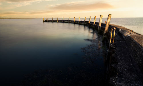 Pier over sea against sky during sunset