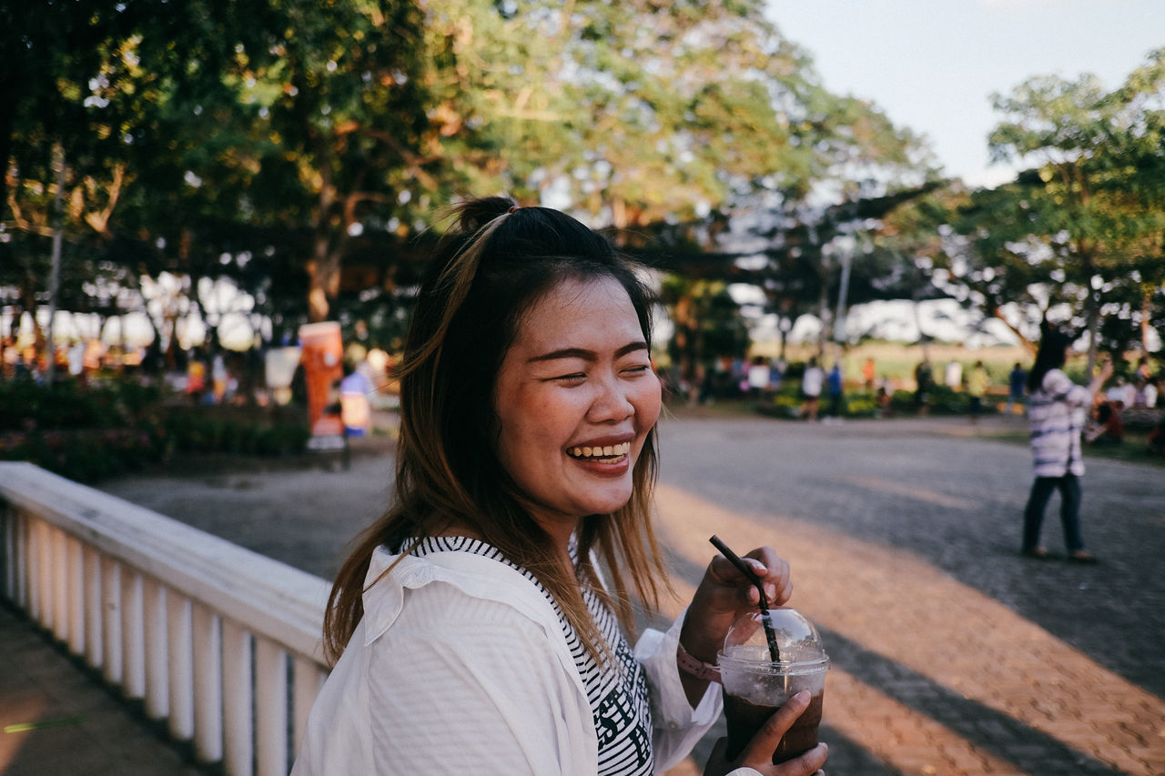 real people, happiness, smiling, lifestyles, leisure activity, one person, women, young adult, young women, emotion, headshot, portrait, focus on foreground, casual clothing, adult, teeth, incidental people, hair, hairstyle, outdoors