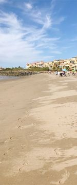 People on beach by buildings against sky