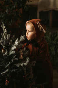 Toddler baby girl in rudolph reindeer costumes decorating christmas tree christmas tree