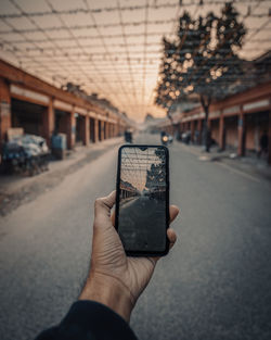 Midsection of person photographing with smart phone on street