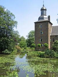 Reflection of trees and buildings in lake against sky