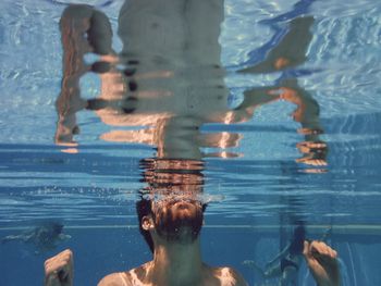 Shirtless man swimming in pool