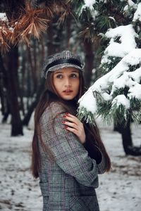 Side view of woman standing in snow covered forest