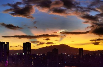Illuminated buildings in city against sky during sunset