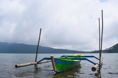 Fishing boats moored in lake against sky