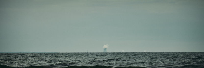 Lighthouse by sea against clear sky