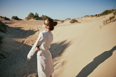 Rear view of woman standing at desert