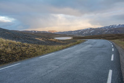 Empty road by mountains against sky