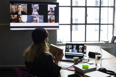 Businesswoman showing product to customers over web conference in board room at office