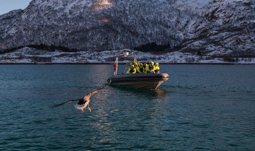 People in boat on sea against mountain