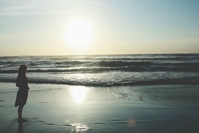 Silhouette woman standing at beach against sky