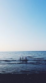 People on beach against clear sky
