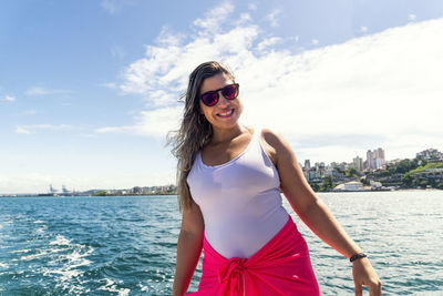 A woman on top of a boat against the sea in the background. 