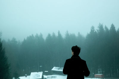 Rear view of man looking at forest during winter