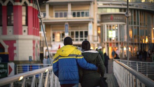 Rear view of friends standing against railing in city