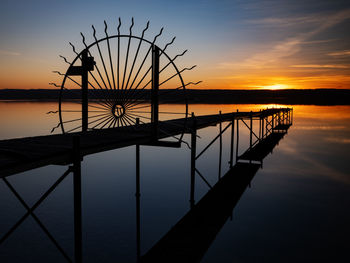 Silhouette pier over sea against sky during sunset