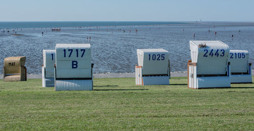 Hooded beach chairs on shore against sky