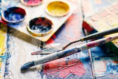 Close-up of paintbrush with palette on messy table