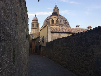 Alley amidst buildings against sky with the view of cathedral dome