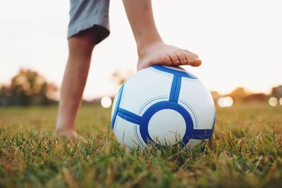 Low section of a boy holding ball under foot