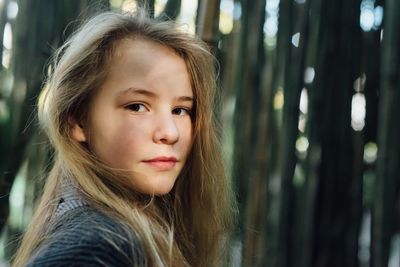 Close-up portrait of teenage girl standing against bamboo grove