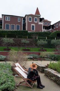 Full length of women sitting by house against building