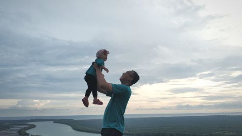 Father and son on sea against sky